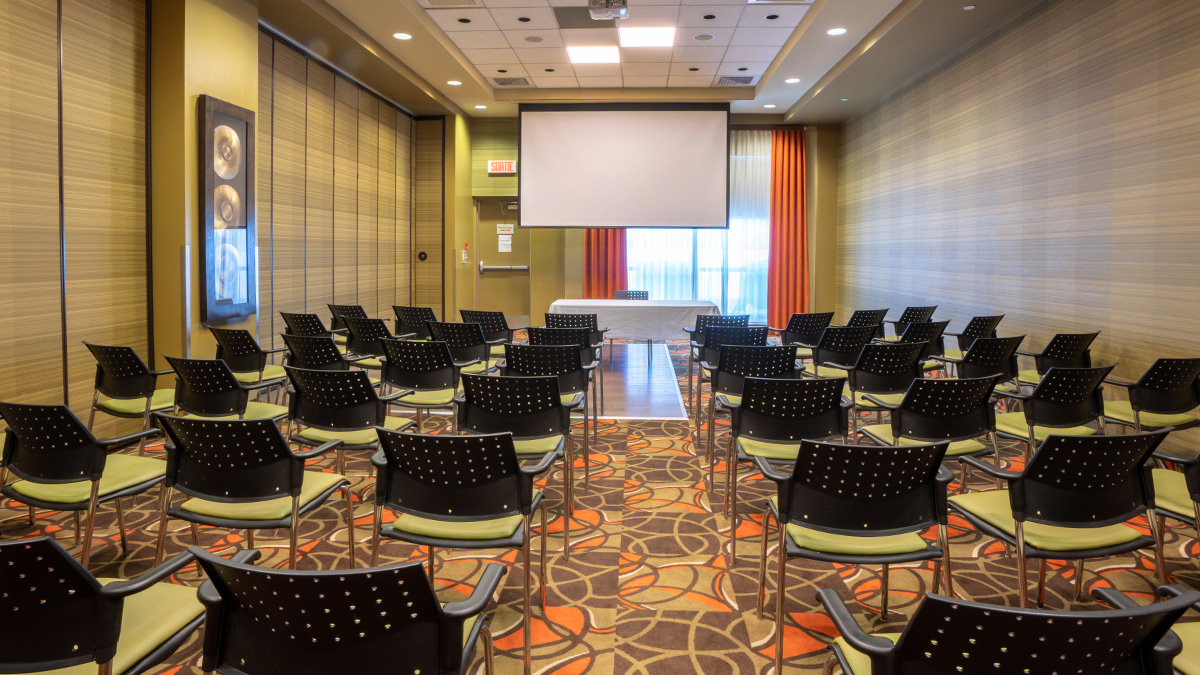 Congrès et Réunions Salle spacieuse équipée de chaises et d'un écran de projection, parfaite pour des événements au Hôtel Must des Hôtels JARO