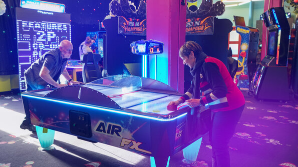 Adults focused on thrilling arcade games at the Carie Factory, in an immersive and entertaining setting.