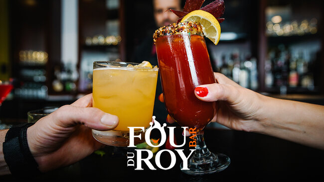 Deux verres à cocktail colorés portés pour un toast, l’un contenant une boisson jaune avec des glaçons, l’autre un cocktail rouge garni de citron et d’épices, devant un bar élégant. Logo du Bar le Fou du Roy au centre, invitant à profiter d’une soirée conviviale avec des cocktails variés.