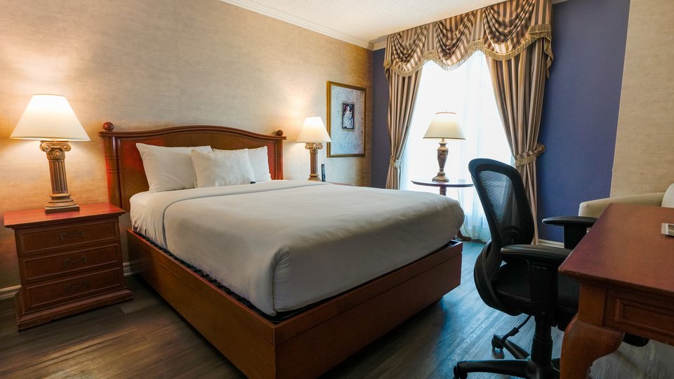 Chambre d’hôtel Palace classique avec un grand lit, un fauteuil et un bureau, offrant une vue imprenable sur la ville de Québec
