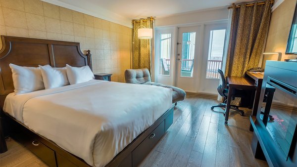 Chambre Confort avec grand lit, télévision, foyer et balcon offrant une vue sur le jardin à l'Hôtel Québec