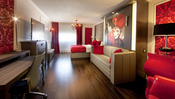 Suite Privilège Rouge Passion avec deux grands lits et un foyer à l'Hôtel Plaza, un décor raffiné aux nuances de rouge et blanc, créant une atmosphère chaleureuse et élégante