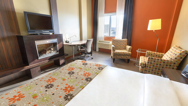 Trendy hotel room with king-size bed, cozy fireplace and TV for a pleasant stay at Hotel Must