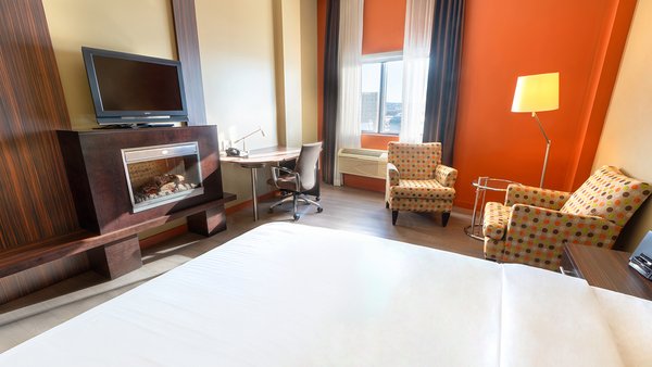 Chambre d'hôtel tendance avec un grand lit, un foyer accueillant et une télévision pour un séjour agréable à l'Hôtel Must