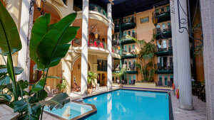  Interior view of Hotel Plaza with a pool surrounded by columns, balconies, and tropical vegetation.