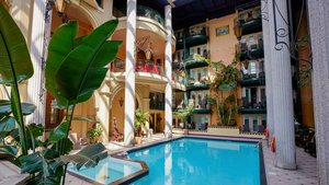 Vue intérieure de l'Hôtel Plaza avec une piscine entourée de colonnes, balcons et végétation tropicale.