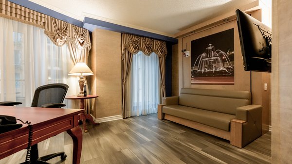 Suite élégante en deux pièces avec canapé, table et chaises, offrant une vue apaisante sur le jardin du Palace Royal