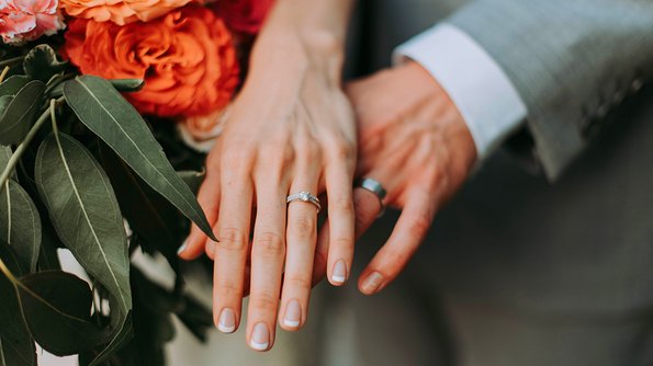 Close-up of a bride and groom embracing hands, symbolizing their commitment and happiness on this unforgettable day at JARO Hotels.