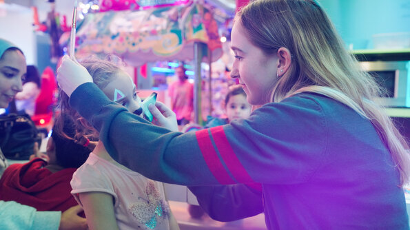 An Easter face painting activity at the Carie Factory, where a child receives a fun face painting from a team member.