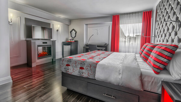 Chambre élégante et accessible avec un très grand lit, ambiance feutrée grâce au foyer et à l’habillage des fenêtres, assurant confort et intimité.