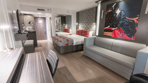 Chambre contemporaine avec deux grands lits, dont un escamotable en canapé, et un balcon offrant une vue sur le jardin à l’Hôtel Plaza