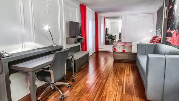 Chambre contemporaine adaptée aux voyageurs en fauteuil roulant, équipée d'un bureau et d'une télévision, avec un balcon offrant une vue imprenable sur le jardin