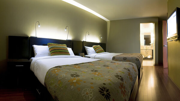 Spacious family suite with three double beds, two separate rooms, TV, whirlpool bath and fireplace, offering comfort and relaxation at the Must Hotel.