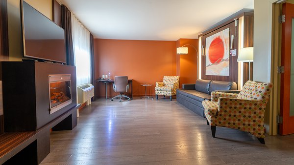 Suite familiale spacieuse avec trois grands lits, deux pièces séparées, télévision, bain-tourbillon et foyer, offrant confort et détente à l'Hôtel Must