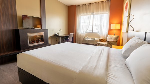 Chambre Tendance Intimité au Québec Inn, avec un grand lit, un divan-lit confortable, une télévision moderne et une décoration élégante pour un séjour chic et agréable à l'Hôtel Must