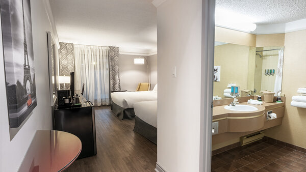 Chambre traditionnelle avec deux lits doubles, salle de bain et terrasse offrant une vue relaxante sur le jardin au Québec Inn