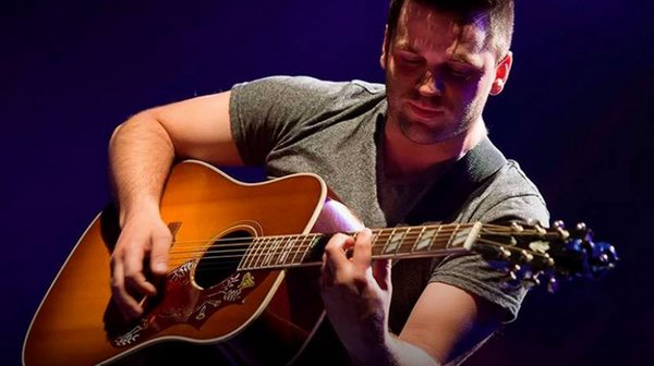 Étienne Cotton lors d'une prestation musicale dans un jardin tropical à L'Hôtel Québec,  avec une ambiance décontractée.