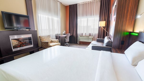 Chambre d'hôtel tendance avec deux grands lits, télévision et foyer chaleureux à l'Hôtel Must.
