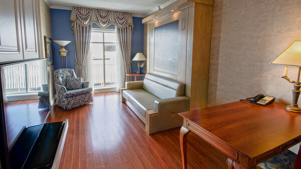 Spacious 2-room suite with sofa, table and chairs, offering a warm and welcoming setting for a comfortable stay.