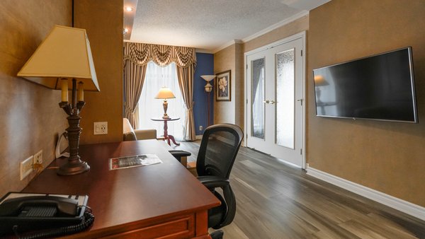 Spacieuse suite de 2 pièces avec un divan, une table et des chaises, offrant un cadre chaleureux et accueillant pour un séjour confortable