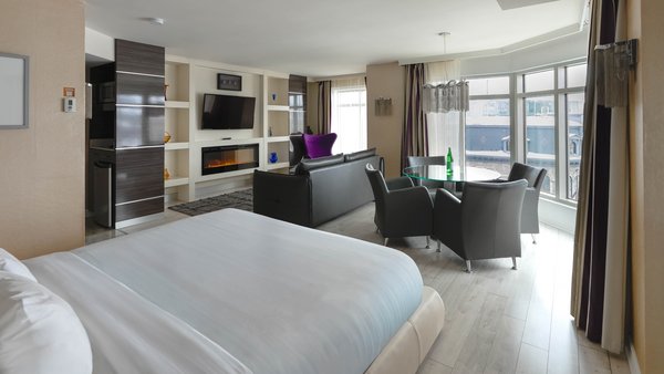 Chambre spacieuse avec un grand lit, un bureau et une télévision, offrant une vue panoramique sur la ville