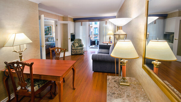 Spacious suite with table and chairs, offering access to a balcony overlooking the Royal Palace garden.