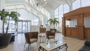Bright space of the Inn with large windows, indoor plants, comfortable armchairs, and elegant wooden decor.