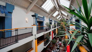 Interior view of Hotel Lindbergh with elegant railings, tropical plants, and a glass ceiling allowing natural light to enter.