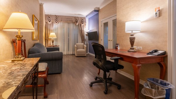 Chambre spacieuse au Palace Royal, composée de deux pièces, avec un grand lit, une commode et une table de nuit, offrant une vue partielle sur le jardin