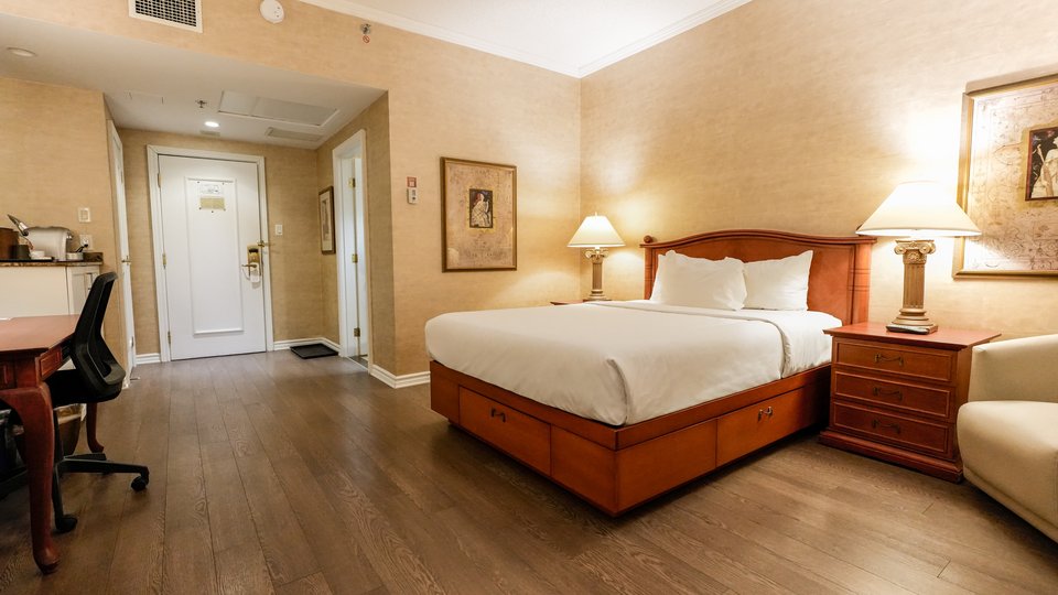 Chambre élégante avec un grand lit, un bureau et une télévision, vue partielle sur le jardin du Palace Royal