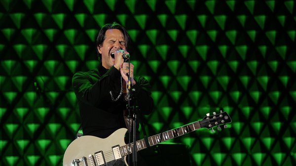 Rémy Langlois se produit sur scène avec sa guitare lors d’un spectacle musical à L’hôtel Québec Inn, dans une ambiance festive illuminée de vert, pour célébrer le Nouvel An.