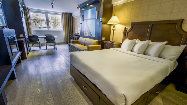 Large hotel room at Hôtel Québec, equipped with three beds, fireplace and television, offering a comfortable space ideal for a relaxing and enjoyable stay.