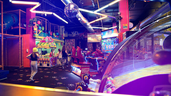 A colourful and lively view of an amusement centre located inside a Must hotel, featuring over 45 arcade games, a maze, the Ball-O-Cité and a 4D carousel.