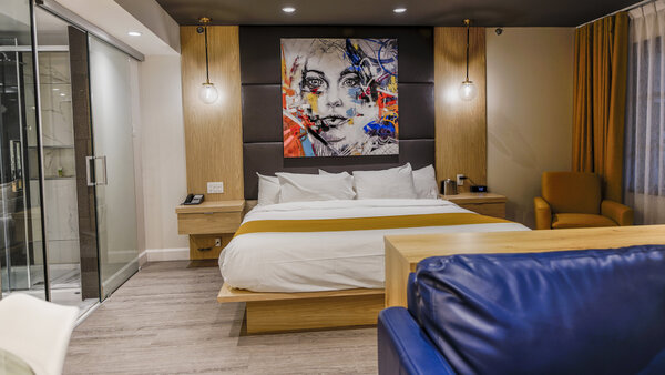 Suite Scandinave avec très grand lit, divan-lit, salle de bain vitrée avec bain autoportant et grande douche, et balcon avec table, 4 chaises et vue sur le jardin de l’Hôtel Québec Inn