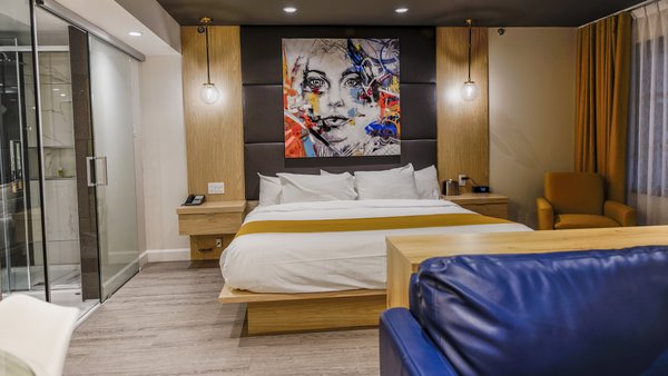 Scandinavian suite with king-size bed, sofa bed, glass-enclosed bathroom with freestanding bathtub and large shower, and balcony with table, 4 chairs and garden view at Hôtel Québec Inn.