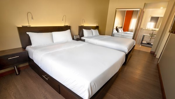 Grande Suite avec trois grands lits, deux pièces séparées et une cuisinette, offrant confort et praticité à l'Hôtel Must.