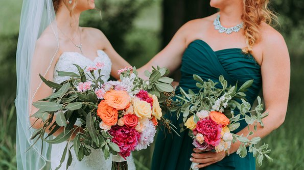 Two radiant bridesmaids pose elegantly, holding magnificent bouquets at a fairytale wedding at JARO Hotels.