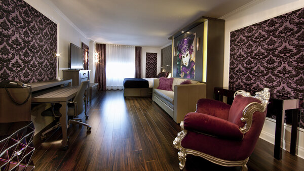 Suite Privilège Brume Mauve avec deux grands lits et un foyer dans l'Hôtel Plaza Québec, décorée avec élégance dans des tons pourpres et un style baroque moderne.