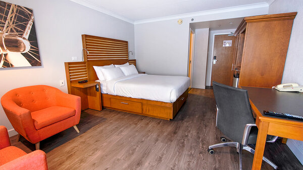 Chambre classique à l'Hôtel Lindbergh avec un grand lit, un bureau et une chaise, offrant un espace confortable et élégant à l'Hôtel Lindbergh