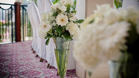 Vibrant flowers in sumptuous vases embellish a table, lending a romantic and refined atmosphere to a wedding hall at JARO Hotels.