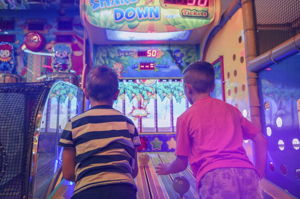 Families have fun together at the Carie Factory, surrounded by colorful arcade games in a warm and dynamic atmosphere.