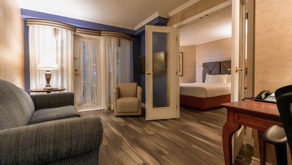  Suite spacieux avec table et chaises, offrant un accès à un balcon surplombant le jardin du Palace Royal