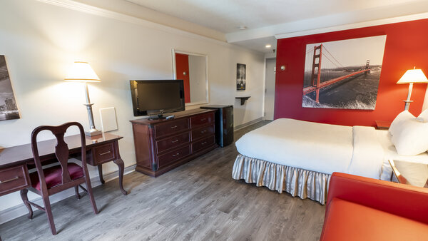 Chambre traditionnelle au Québec Inn avec grand lit, divan-lit confortable et balcon offrant une vue apaisante sur le jardin luxuriant.