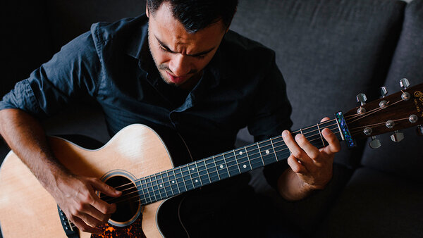 Thierry Gomez jouant de la guitare acoustique lors d'une prestation musicale à L'Hôtel Plaza.