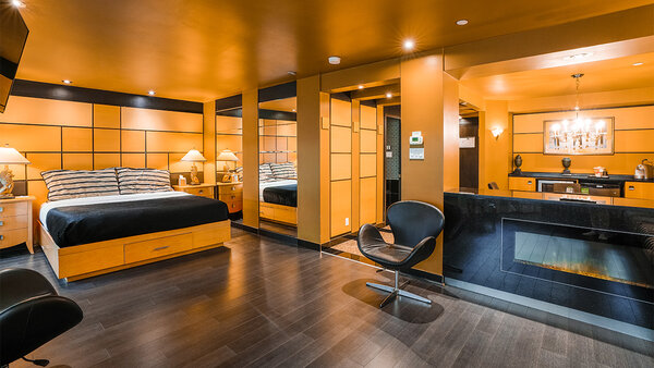 Suite Art Déco avec très grand lit, divan-lit, bain à remous double, grande douche et balcon avec table, 4 chaises et vue sur le jardin de l’Hôtel Québec Inn.