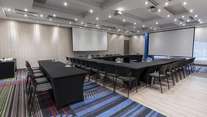 Salle d'événements de L'Hôtel Québec, lumineuse et moderne, avec projecteurs, écrans géants et disposition élégante pour réunions et célébrations