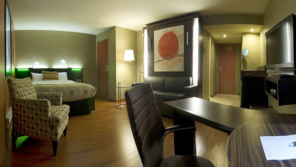 Trendy hotel room with two large beds, desk, chair and TV, windowless, offering an intimate and comfortable space at Hotel Must.