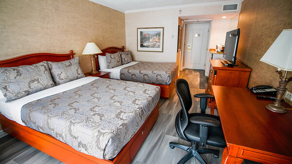 Classic hotel room with two double beds and a desk, overlooking the outside of the Royal Palace.