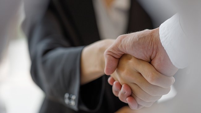 Plan rapproché d'une poignée de main professionnelle symbolisant l'engagement des Hôtels JARO à offrir des services exceptionnels pour les événements d'affaires, avec des salles polyvalentes et des ententes personnalisées.