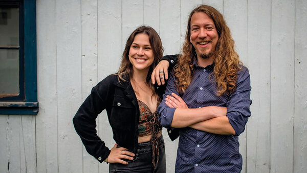 Photo of musical duo The Flips in front of a light background, smiling and relaxed.